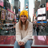 Woman wearing yellow Liberty Roots 1776 beanie on Times Square red stairs